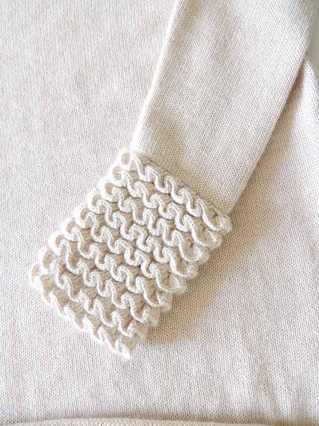 Knitted sweater light beige in soft baby alpaca with a round neckline, cuffs and neck rushes pattern.